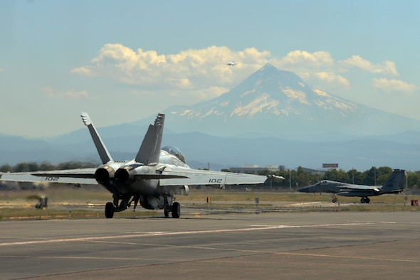 A U.S. Navy F-18F Super Hornet from VFA-41 squadron, based out of Naval Air Station Lemoore, Calif., taxis along the flightline with an F-15C Eagle, assigned to the 142nd Fighter Wing at the Portland Air National Guard Base, Portland, Ore., during an afternoon sortie as part of dissimilar aircraft combat training (DACT) on Aug. 13, 2019. The two-week training exercise from Aug. 11-23 provides realistic combat scenarios for pilots to hone advanced aerial tactics used against potential adversaries. (U.S. Air National Guard photo by Master Sgt. John Hughel)