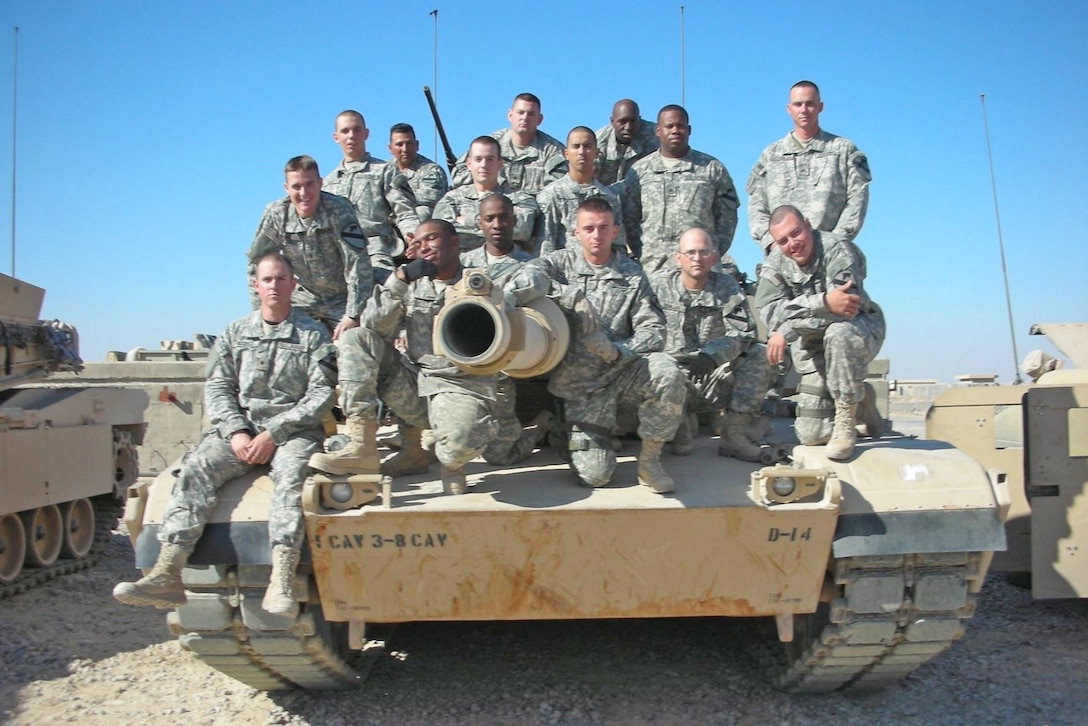 Soldiers pose for a photo on a tank.