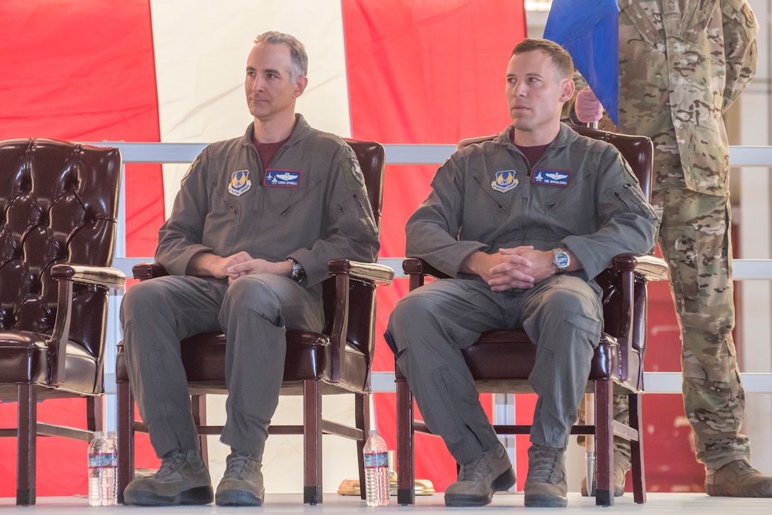 Col. Christopher J. Spinelli and Col. Timothy J. Spaulding sit side by side listening to Brig. Gen. E. John "Dragon" Teichert delivering opening remarks at the change of command ceremony.