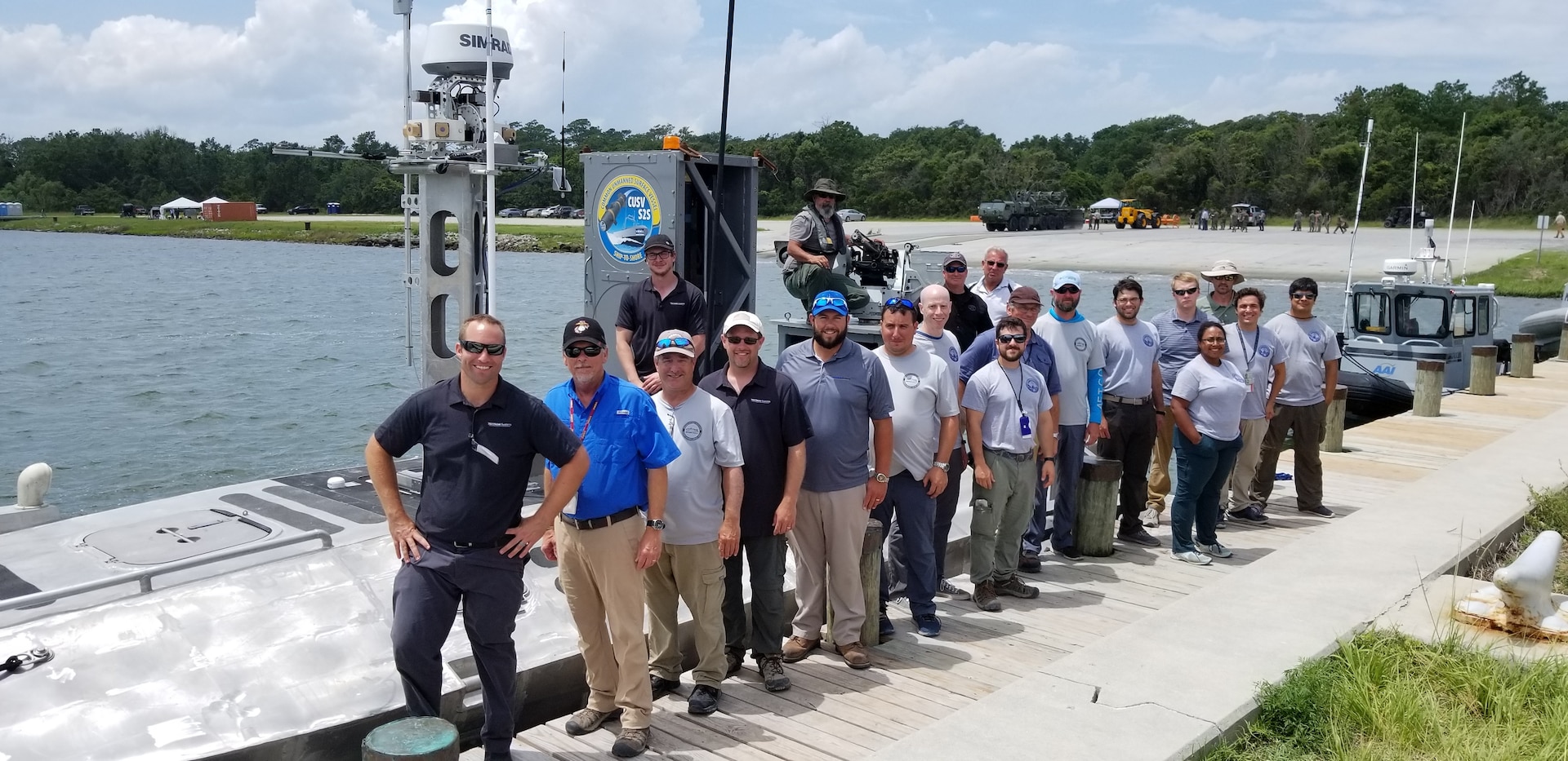 IMAGE: CAMP LEJEUNE, N.C. (July 19, 2019) — The Navy-industry Cooperative Research and Development Agreement (CRADA) team that developed the Expeditionary Warfare Unmanned Surface Vessel (USV) is pictured at the 2019 Advanced Naval Technology Exercise (ANTX). The team – comprised of Naval Surface Warfare Center Dahlgren Division (NSWCDD) and Textron Systems scientists and engineers – demonstrated the Expeditionary Warfare USV’s ability to control inshore and littoral areas while identifying and engaging remote targets. NSWCDD unmanned system experts worked with their industry partner under the CRADA to integrate expeditionary warfare payloads they developed and integrated onto Textron’s Common Unmanned Surface Vehicle.  (U.S. Navy photo/Released)