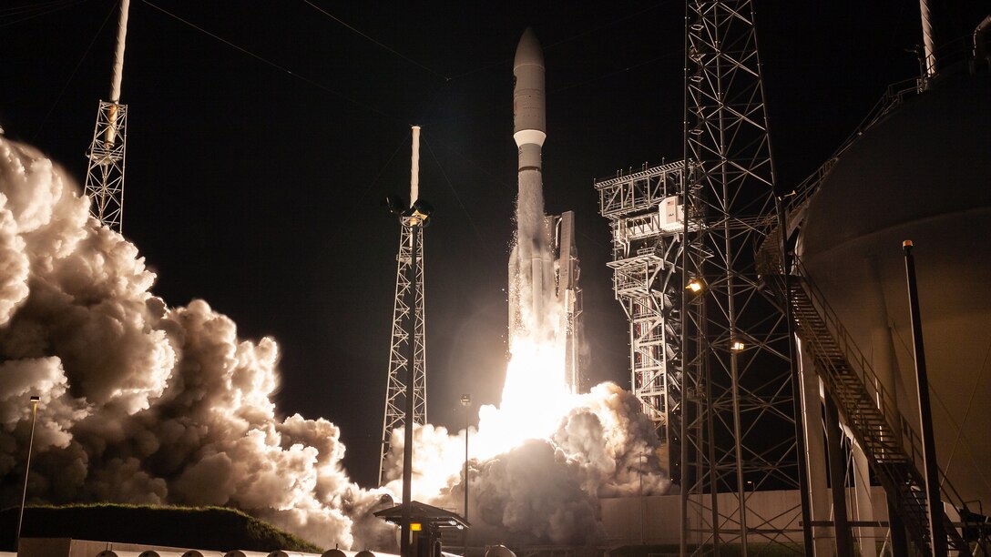 A rocket launching at night with vapors billowing to the left