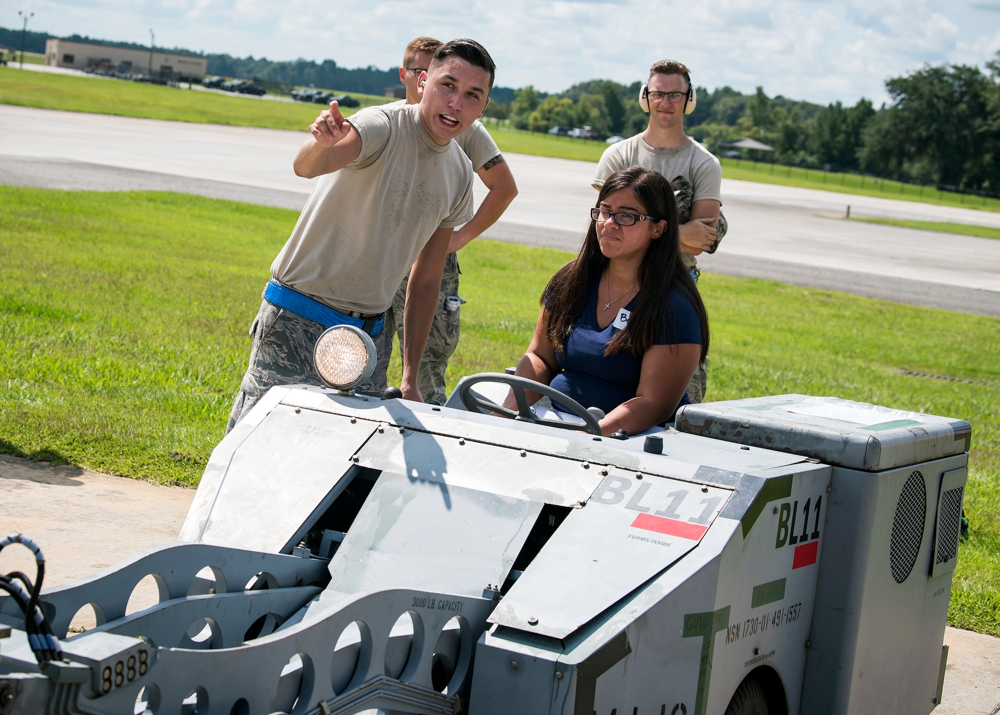 An Airman from the 23d Aircraft Maintenance Squadron (AMXS), left, gives instruction on how to operate a MJ1-B munition handler Aug. 23, 2019, at Moody Air Force Base, Ga. Spouses and family members from the 23d AMXS toured the squadron and flightline to gain a first-hand understanding of what role their significant other plays in the mission. The tour also served as a way to expand support networks by connecting spouses and family members with unit personnel. (U.S. Air Force photo by Airman 1st Class Eugene Oliver)