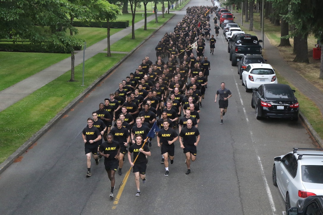 A long line of soldiers in matching sweats run down a street.