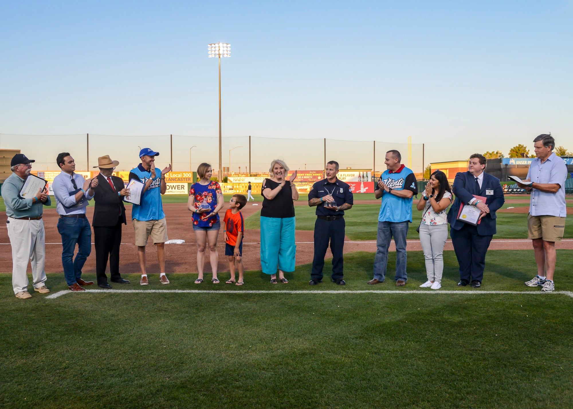 Tech. Sgt. Janna Ybarra, 412th Medical Group, and Lead Firefighter James Levell, 812th Civil Engineer Squadron (pictured with awards) are applauded after receiving the Bank of America/Merrill Military Service Before Self Award during a Lancaster JetHawks game at the Hangar baseball stadium in Lancaster, California, Aug. 24. (U.S. Air Force photo by Giancarlo Casem)