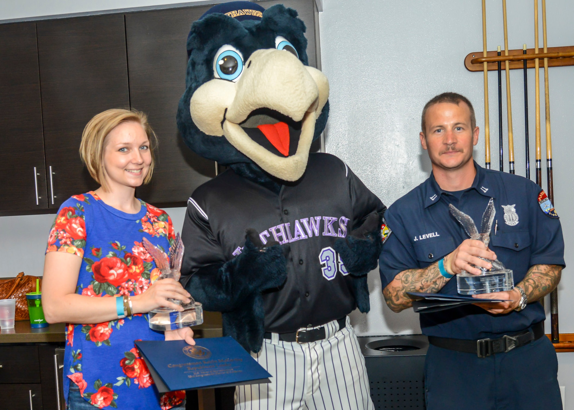 Tech. Sgt. Janna Ybarra, 412th Medical Group, and Lead Firefighter James Levell, 812th Civil Engineer Squadron, pose with JetHawks mascot, KaBoom, during a Lancaster JetHawks game at the Hangar baseball stadium in Lancaster, California, Aug. 24. The pair were honored by local civic leaders for their service to the Air Force and the local community. (U.S. Air Force photo by Giancarlo Casem)