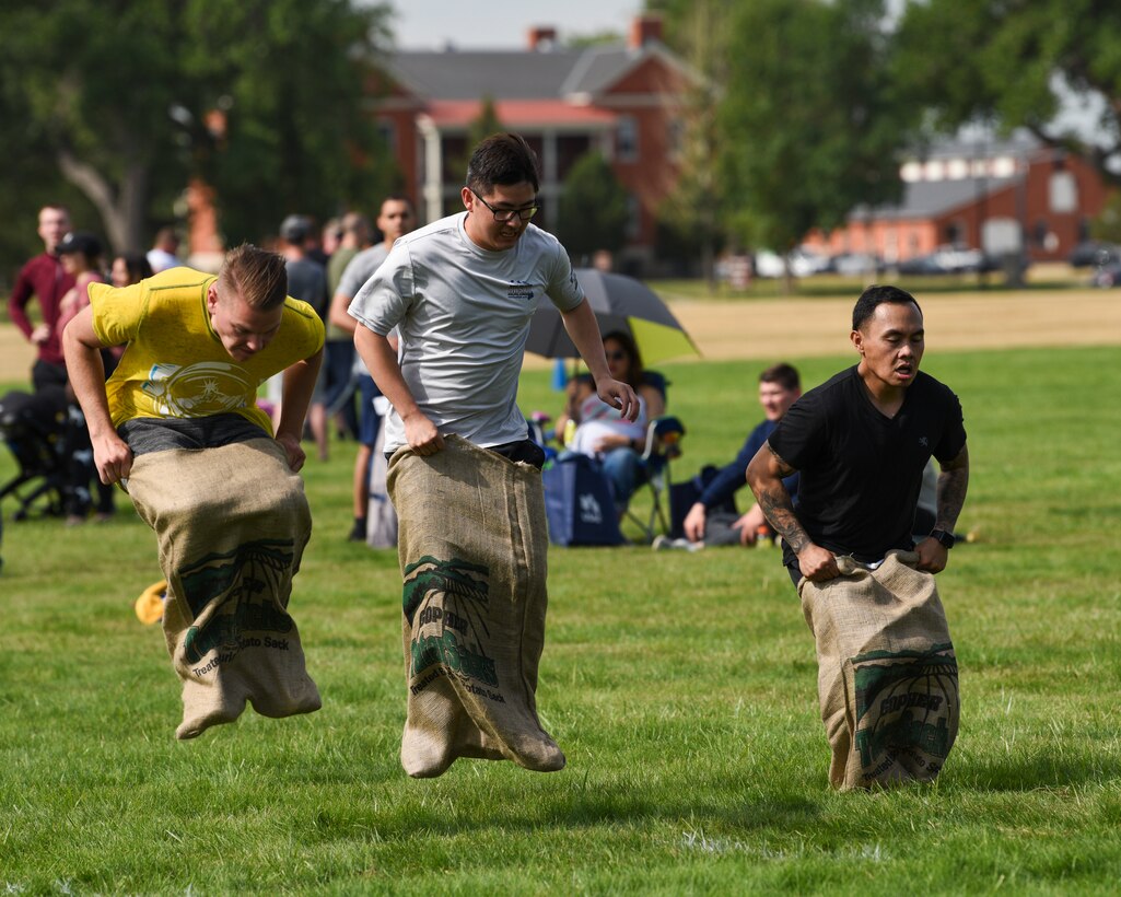 Three Airmen hop during a potato sack race on Aug. 23, 2019, during the annual Frontiercade on F.E. Warren Air Force Base, Wyo. Along with the potato sack race, 12 other activities compiled competing squadrons into winning or losing brackets. (U.S. Air Force photo by Staff Sgt. Ashley N. Sokolov)