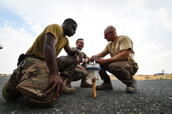 Staff Sgt. Raul Cancel, 386th Expeditionary Civil Engineer Squadron electrical systems craftsman, works with Airman Nicholas Lee, 386th ECES electrical systems journeyman, and a contractor while replacing a solar-powered taxiway light at Ali-Al Salem Air Base, Kuwait, Aug. 14, 2019. The most common reasons lights require replacing are getting hit by an object and burning out over time. (U.S. Air Force photo by Senior Airman Lane T. Plummer)