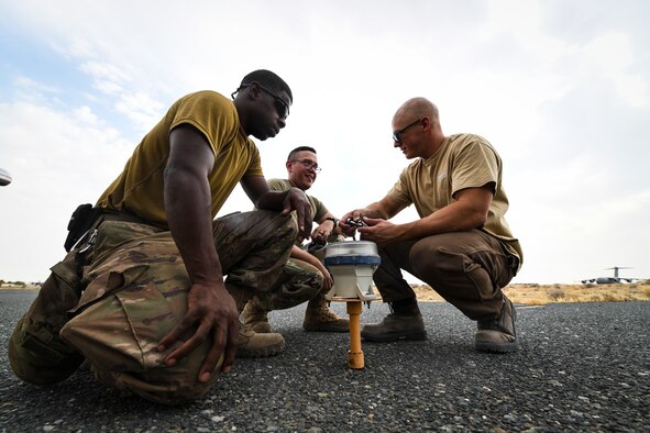 Staff Sgt. Raul Cancel, 386th Expeditionary Civil Engineer Squadron electrical systems craftsman, works with Airman Nicholas Lee, 386th ECES electrical systems journeyman, and a contractor while replacing a solar-powered taxiway light at Ali-Al Salem Air Base, Kuwait, Aug. 14, 2019. The most common reasons lights require replacing are getting hit by an object and burning out over time. (U.S. Air Force photo by Senior Airman Lane T. Plummer)