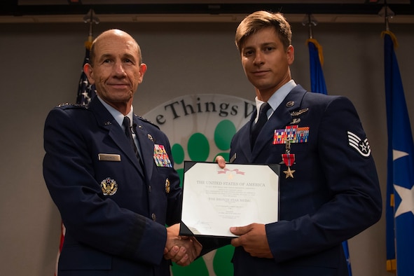 U.S. Air Force Gen. Mike Holmes, left, commander of Air Combat Command, presents a Bronze Star Medal with Valor citation to Staff Sgt. Aaron Metzger, right, 38th Rescue Squadron pararescueman, Aug. 26, 2019, at Moody Air Force Base, Ga. Metzger was awarded the medal because of his engagement in action against an enemy while deployed to Afghanistan in 2018. (U.S. Air Force photo by Airman 1st Class Taryn Butler)