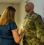 Newly promoted Maj. Shawn Robertson’s wife, Sarah, places his new rank on his uniform during a promotion ceremony Aug. 23.