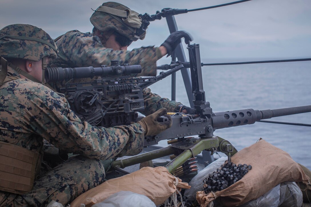 Two Marines fire a machine gun.