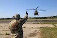 Master Sgt. Jack Kenyon, course manager for the 89B Ammunition Supply Course with the 13th Battalion, 100th Regiment at Fort McCoy, Wis., provides lift guidance from a distance Aug. 1, 2019, to a Chinook helicopter crew during sling-load training for the course at Sparta-Fort McCoy Airport.