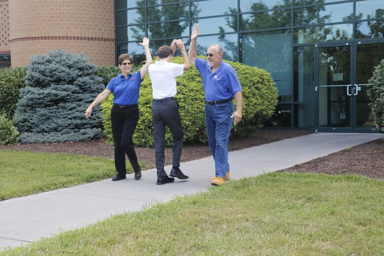 Carol and Bob Hickel high-five their son David Hickel as they leave the Middle East District Headquarters in Winchester, Va., and David, a summer intern with the District, enters. Carol is working as a rehired annuitant and Bob is preparing to retire after a 10-year career with the District.