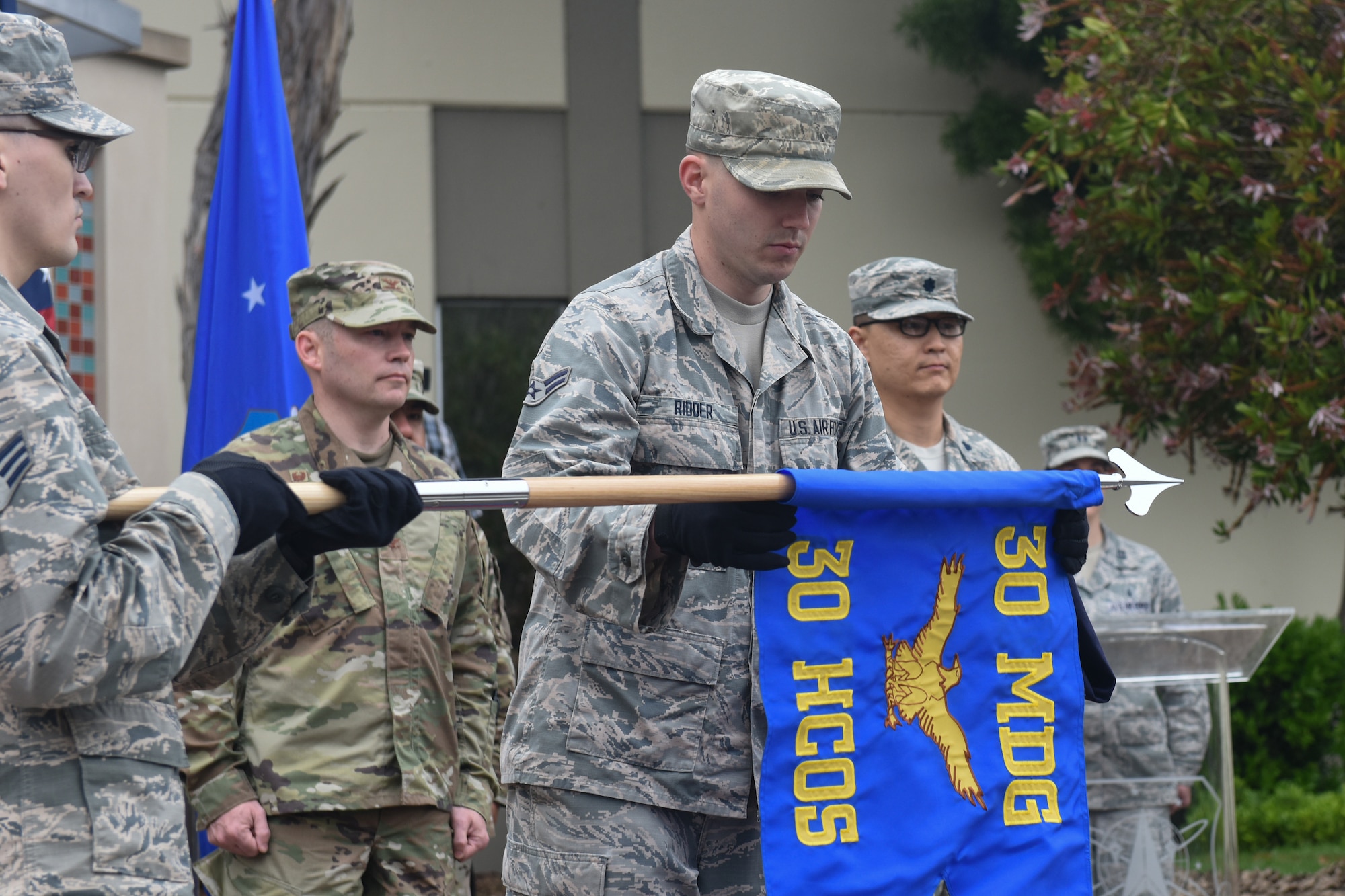Airman First Class Thomas Ridder, Vandenberg Color Guard member, unfurls a guidon for the newly activated 30th Health Care Operations Squadron during the 30th MDG reorganization ceremony Aug. 23, 2019, at Vandenberg Air Force Base, Calif.