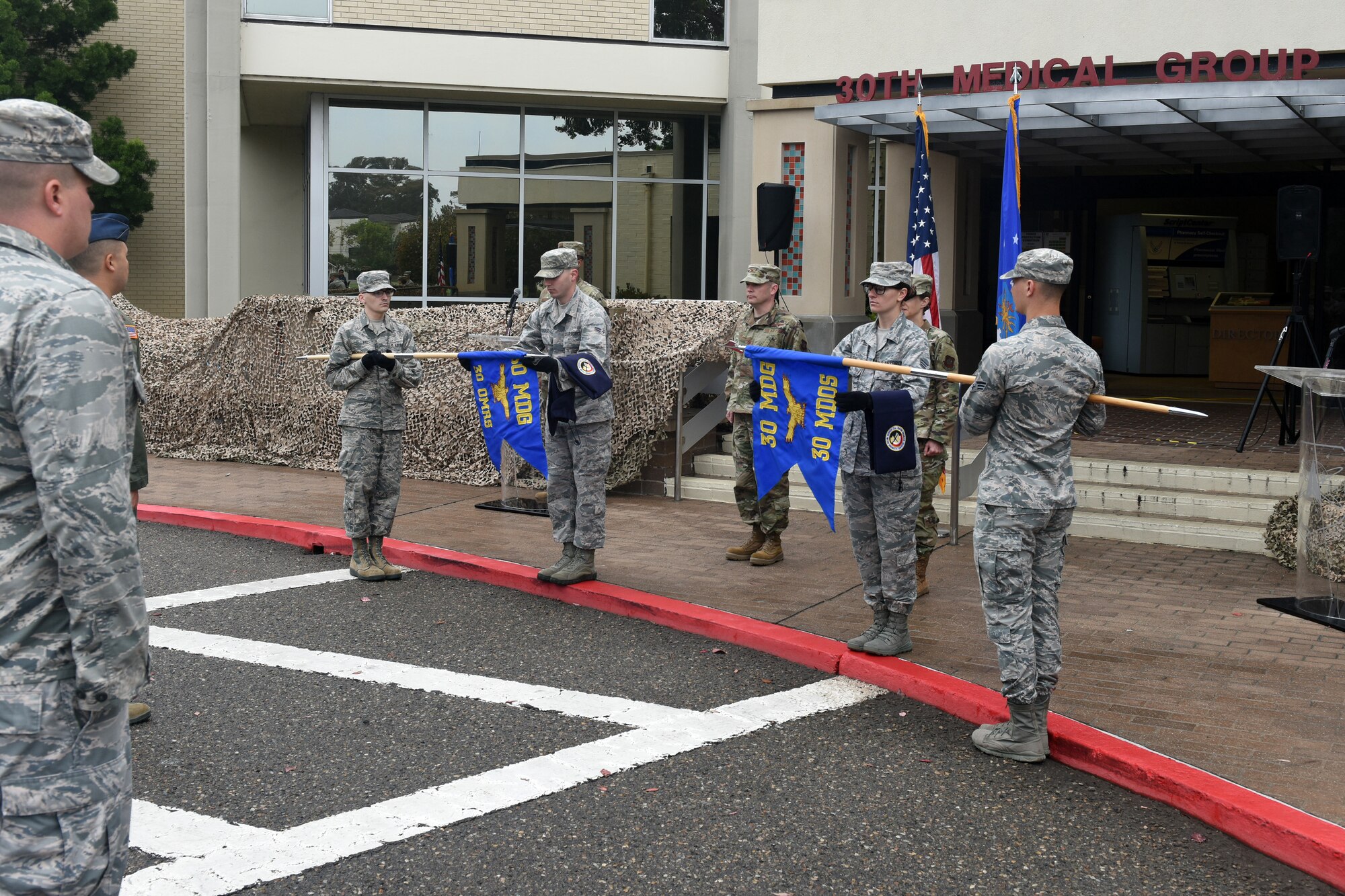 Vandenberg Color Guard team members simultaneously furl the guidon of the 30th Medical Operations Squadron and unfurl the guidon of the redesignated 30th Operational Medical Readiness Squadron during the 30th Medical Group reorganization ceremony Aug. 23, 2019, at Vandenberg Air Force Base, Calif.