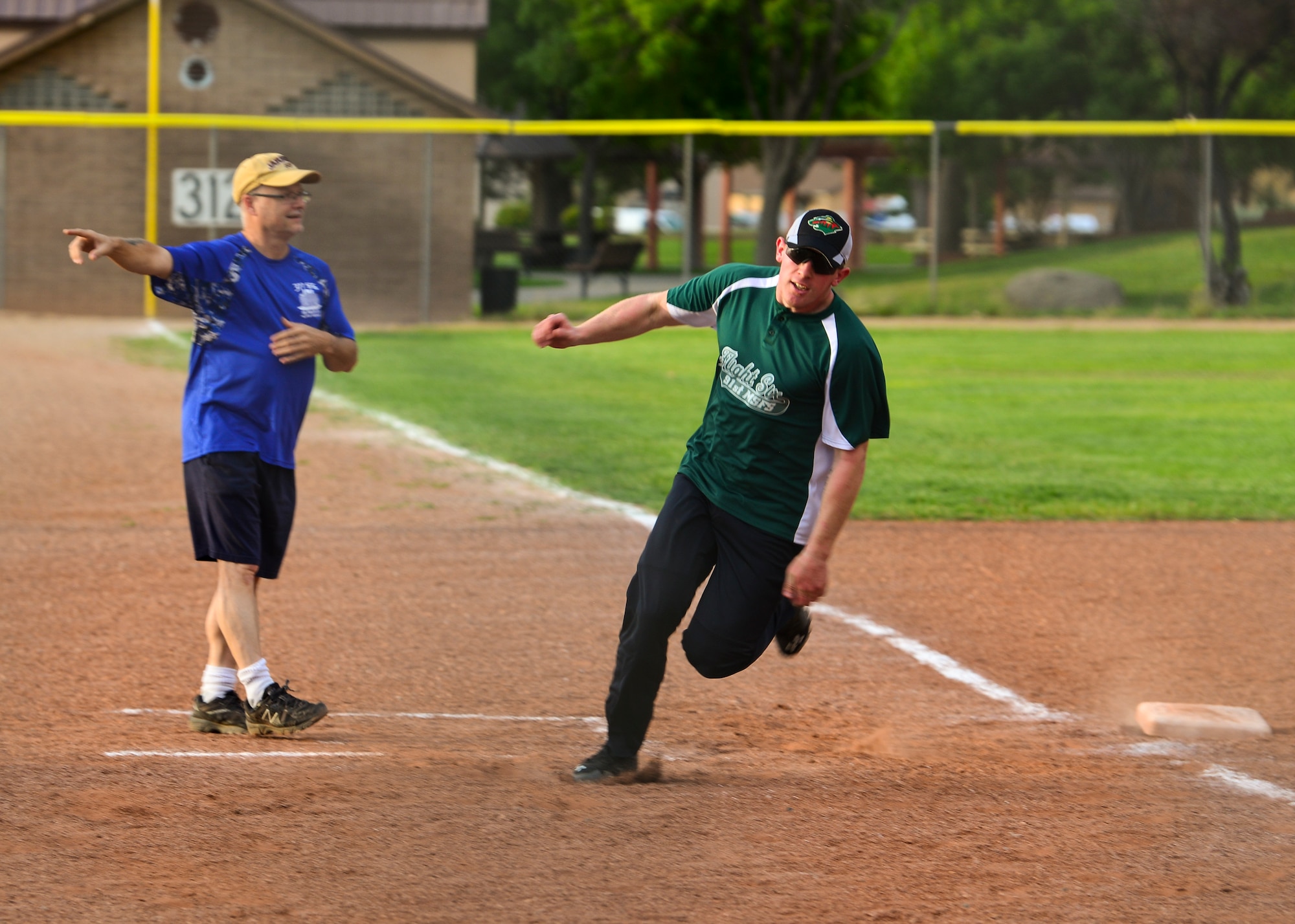 Marcus Rinehart (left) captain for Team SFS, directs James Tienor, outfielder for Team SFS, to run home at the 2019 Kirtland Softball Intramural Championship Game at Kirtland Air Force Base, N.M., August 22, 2019. The 2019 softball season consisted of 13 regular season games with a single-elimination playoff tournament to determine the champion. (U.S. Air Force photo by Airman 1st Class Austin J. Prisbrey)