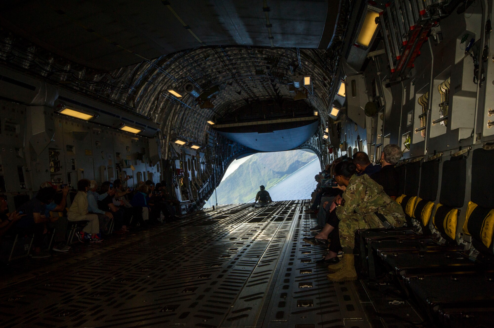 A U.S. Air Force C-17 Globemaster III banks as a loadmaster sits on the back ramp, while members of the Pacific Air Forces’ Air Force Civilian Advisory Council take photos during a simulated cargo drop over waters off the coast of Hawaii, Aug. 20, 2019. Thirty-one AFCAC civic leaders attended a PACAF-hosted C-17 civic leader flight where they witnessed two refueling efforts by a KC-135 Stratofortress and one simulated C-17 cargo drop. (U.S. Air Force photo by Staff Sgt. Jack Sanders)