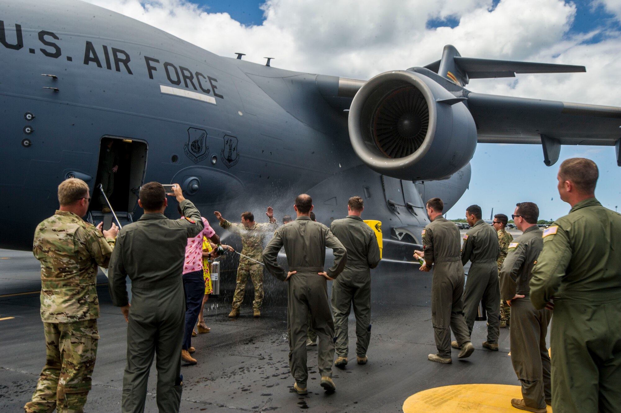 Friends and family shower Maj. Freddy Rodriguez and Staff Sgt. Ryan Myers with water and Champaign, an Air Force tradition, after their “fini” or final flight as part of the squadron at Joint Base Pearl Harbor-Hickam, Hawaii, Aug 20, 2019. Myers and Rodriguez’s “fini” flight celebration demonstrated a rich tradition to 31 members of the Pacific Air Forces’ Air Force Civilian Advisory Council civic leaders who attended the PACAF-hosted C-17 civic leader flight where they also witnessed two refueling efforts by a KC-135 Stratofortress and one simulated C-17 cargo drop. (U.S. Air Force photo by Staff Sgt. Jack Sanders)