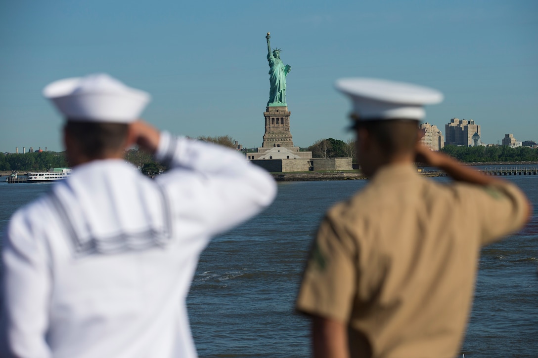 Two sailors salute the Statue of Liberty.