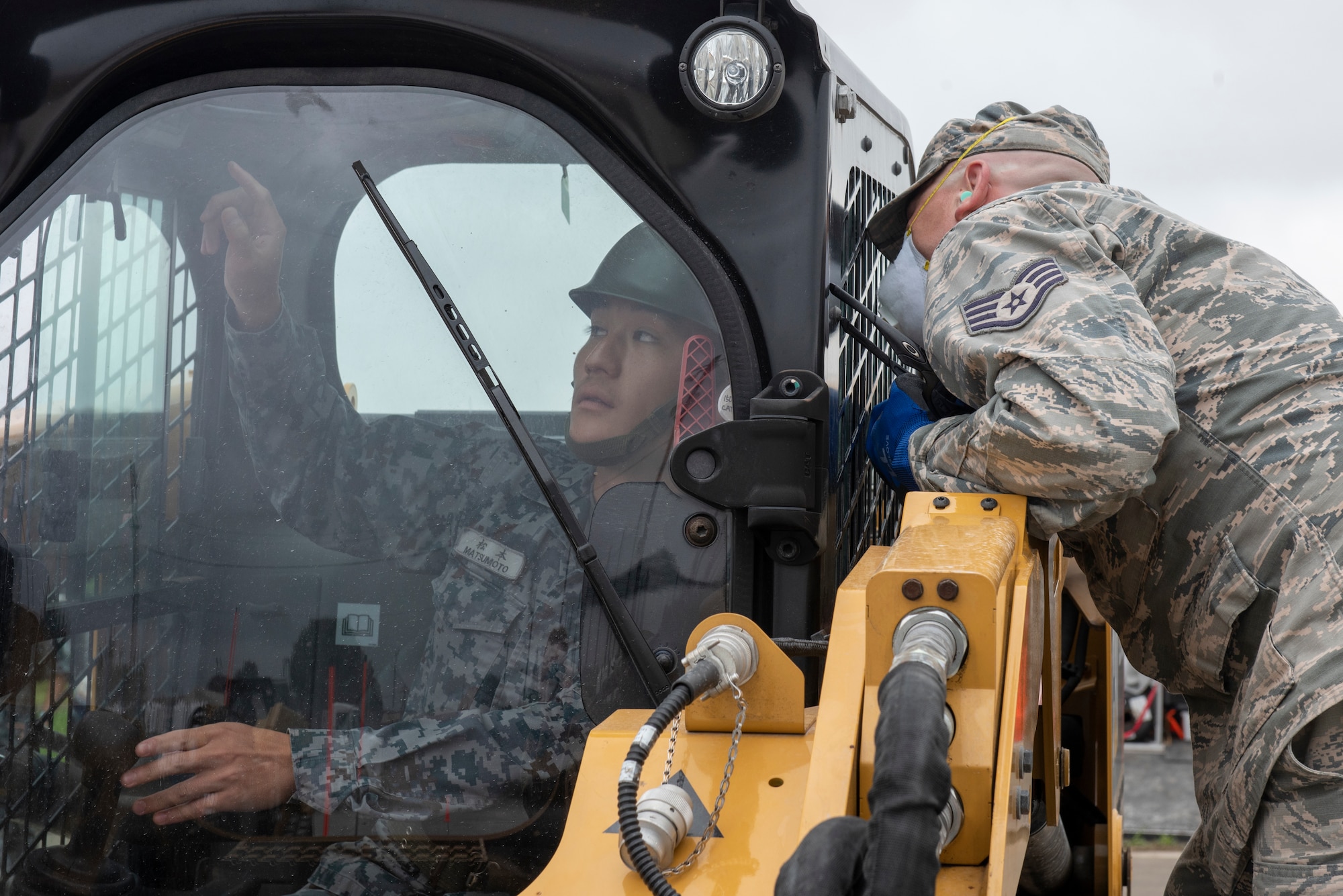 An Airman from the 374th Civil Engineer Squadron communicates with his Japan Air Self-Defense Force counterpart to better position equipment during the hands on portion of Pacific Unity 2019 at Yokota Air Base, Japan, August 22, 2019.