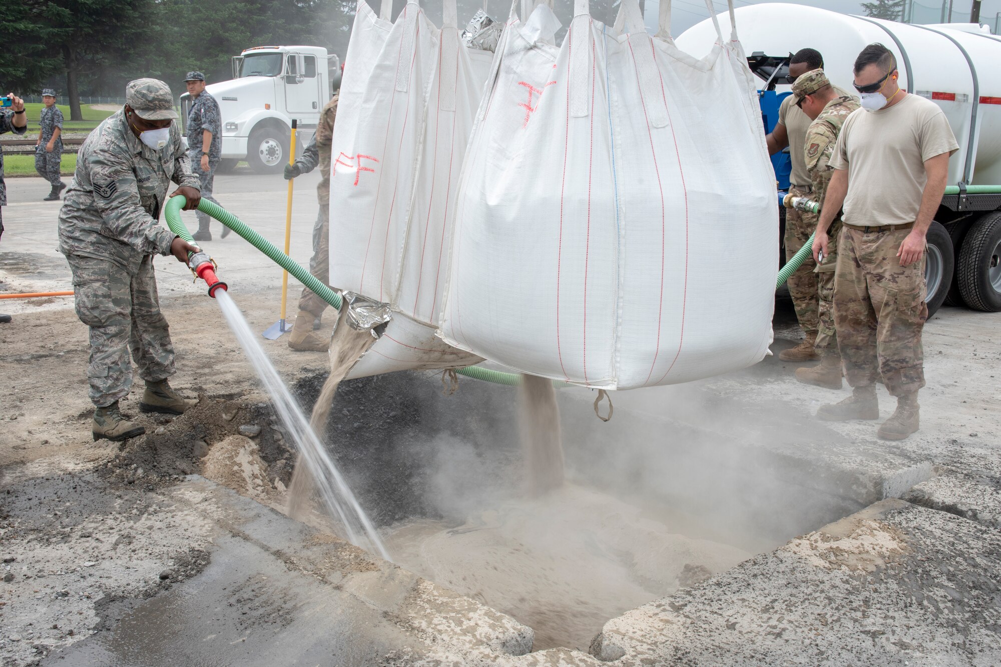 Civil Engineer Airmen mix water with flow able fill rapid set concrete to complete the backfill portion of rapid airfield damage repair (RADR) during Pacific Unity 2019 at Yokota Air Base, Japan, August 22, 2019.