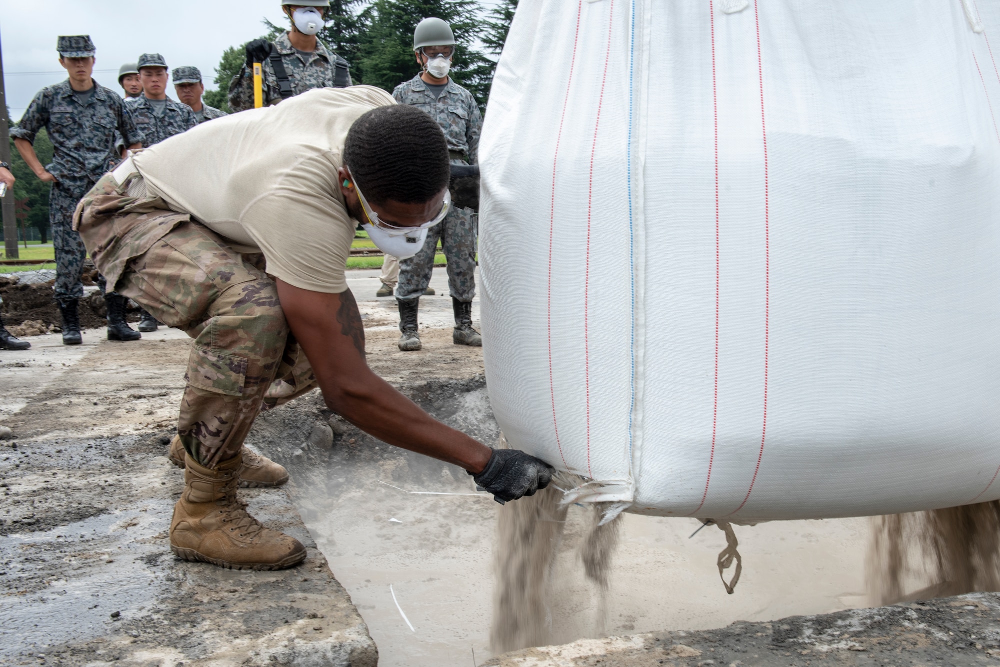 Staff Sgt. Shannon Anderson, 51st Civil Engineer Squadron electrical systems craftsman out of Osan Air Base, Republic of Korea, cuts open a bag of flow able fill rapid set concrete to be mixed with water to complete the backfill portion of rapid airfield damage repair (RADR) during Pacific Unity 2019 at Yokota Air Base, Japan, August 22, 2019.