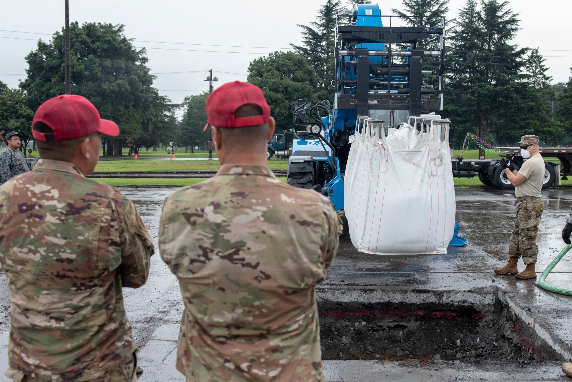 Training cadre from the 554th RED HORSE Squadron out of Andersen Air Force Base, Guam, oversee a civil engineer Airman position equipment prior to backfilling a crater while conducting rapid airfield damage repair (RADR) during Pacific Unity 2019 at Yokota Air Base, Japan, August 23, 2019.