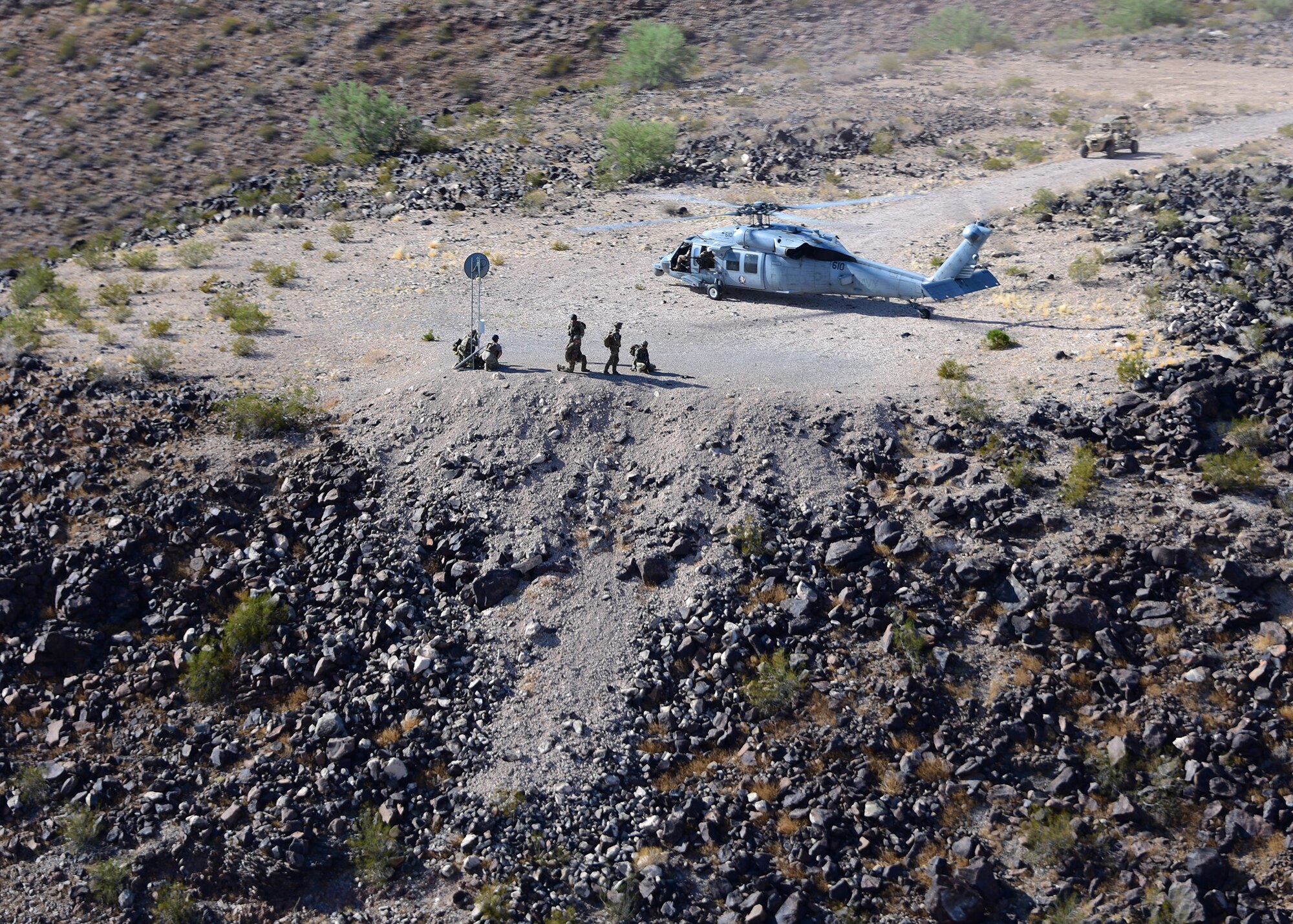 a photo of a Naval unit and helicopter sitting on a dirt training area