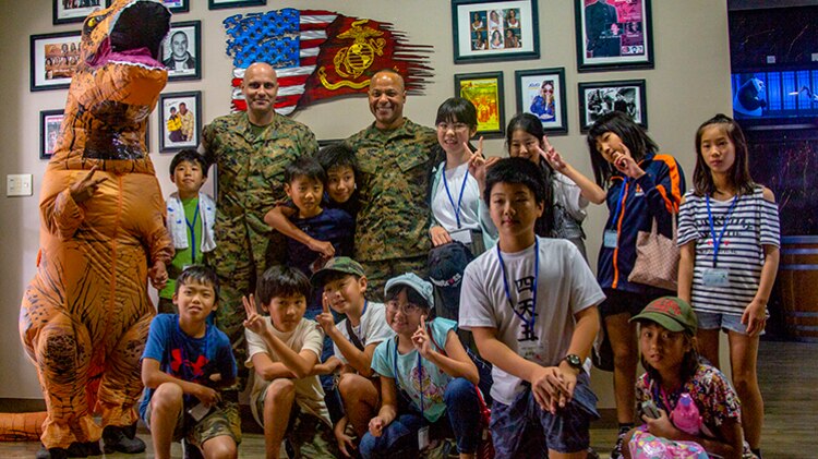 Japanese schoolchildren pose for a photograph with U.S. Marine Corps Sgt. Maj. Jonathan M. Wyble, left, the Combined Arms Training Center (CATC) Camp Fuji sergeant major, and Sgt. Maj. Vincent F. Young, the Marine Corps Installations Pacific sergeant major, during the National Chuo Youth Friendship Center's third annual English camp at CATC Camp Fuji, Shizouka, Japan Aug. 24, 2019. 30 children from the local community were chosen out of over 300 applicants to participate in the English camp.