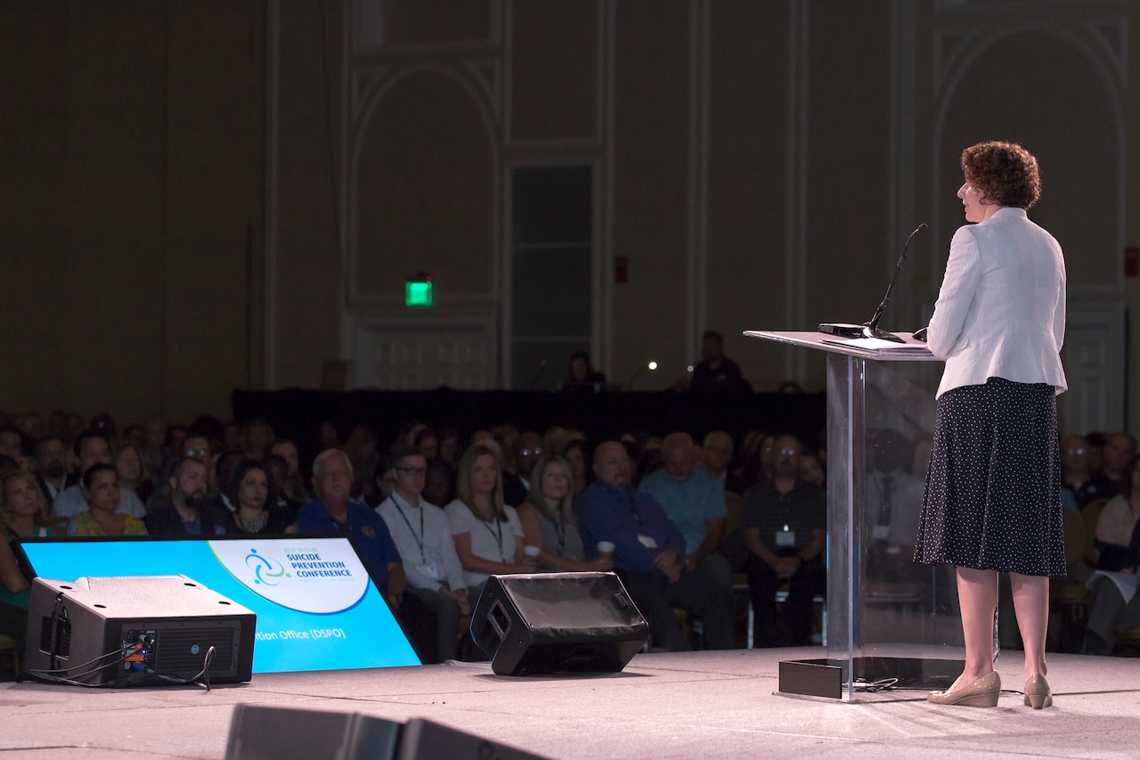 A woman makes a speech from a stage.