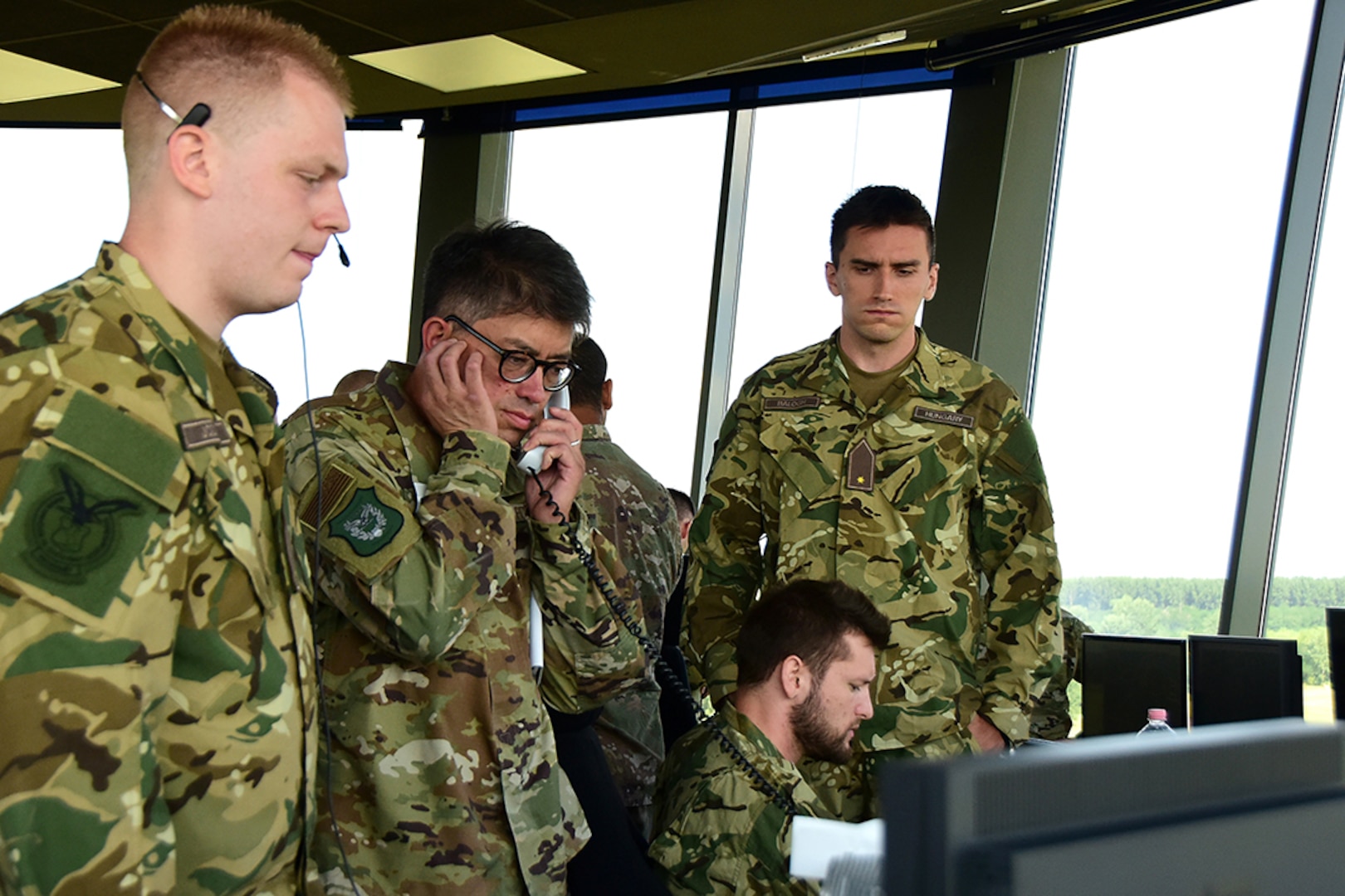 U.S. Air Force Lt. Col. Allen Kao, a public health officer assigned to the 179th Medical Group, answers the phone and works alongside his Hungarian counterparts during a simulated in-flight emergency response exercise Aug. 1, 2019, at Pápa Air Base, Hungary. The simulation was a part of a three-weeklong intermediate airfield management course that an Ohio National Guard mobile training team led for its Hungarian partners. Ohio and Hungary have been paired through the Department of Defense State Partnership Program since 1993.