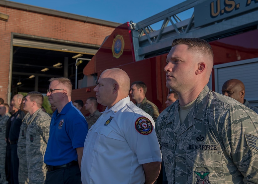 Staff Sgt. Bryan Thacker, right, a firefighter assigned to the 628th Civil Engineer Squadron Fire Department, and other members of the Fire Department stand in formation during a push-in ceremony at Joint Base Charleston, S.C. Aug. 27, 2019. The push-in ceremony was a way for the Fire Department to welcome two new firetrucks to their fleet, a P-26 water tanker and a P-26 aerial apparatus, and was the first of its kind at JB Charleston. Push-in ceremonies date back to when firefighters responded with horses and carriages and pushed their carriages back into stalls after returning from a call.