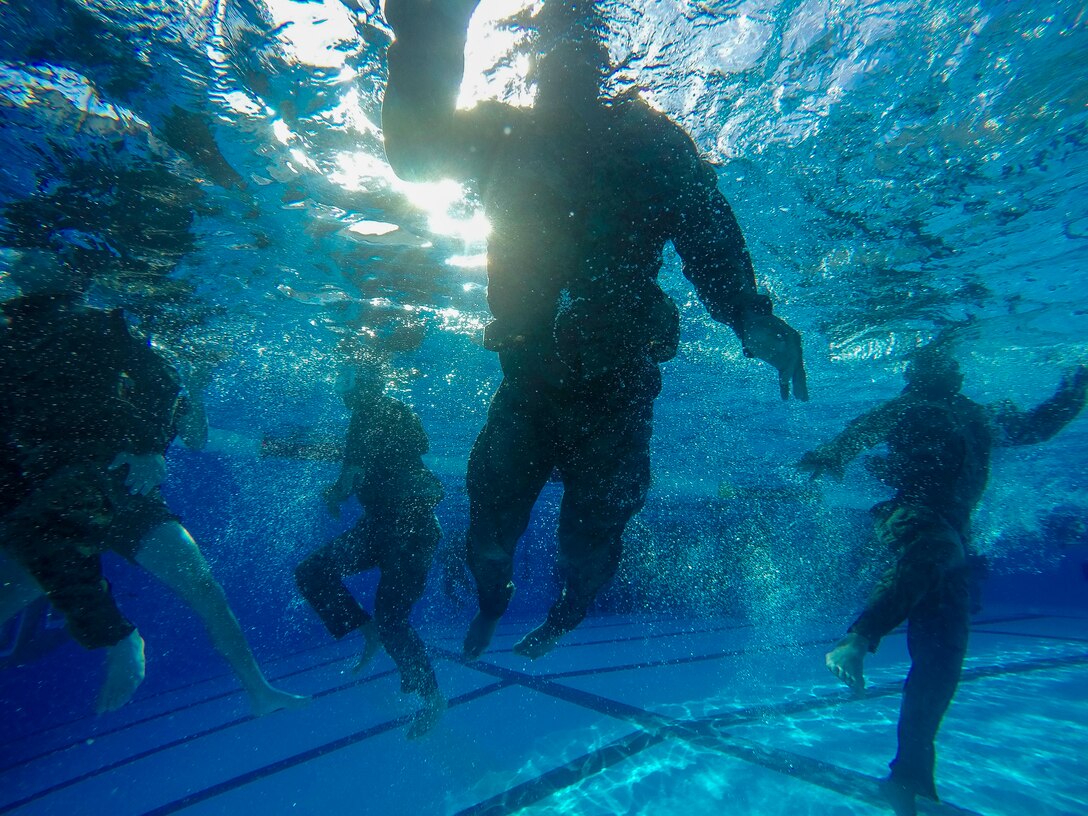 Marines exercising underwater in a pool.