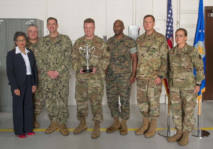 U.S. Air Force Col. Jeffrey Schreiner, center, holds the Omaha Trophy with the U.S. Strategic Command official party after the awards presentation on Aug. 27, 2019, at Whiteman Air Force Base, Missouri. The Omaha Trophy is awarded by the Strategic Command Consultation Committee to units for excellence in strategic deterrence and support of global strike operations. The active-duty 509th Bomb Wing and Missouri Air National Guard’s 131st Bomb Wing jointly earned the Omaha Trophy for executing the best Strategic Bomber Operations of 2018. From left, the Honorable Rita Sanders, representing the SCC; U.S. Air National Guard Col. Kenneth Eaves, 131st Bomb Wing commander; U.S. Navy Vice Adm. Dave Kriete, STRATCOM deputy commander; Col. Jeffrey Schreiner; U.S. Marine Corps Master Gunnery Sgt. Terrence Meekins, STRATCOM Headquarters commandant; U.S. Air Force Chief Master Sgt. Ziegelbein, acting command chief 509th Bomb Wing and Chief Master Sgt. Jessica Settle, 131st command chief. (U.S. Air Force Photo by Airman 1st Class Thomas Johns)