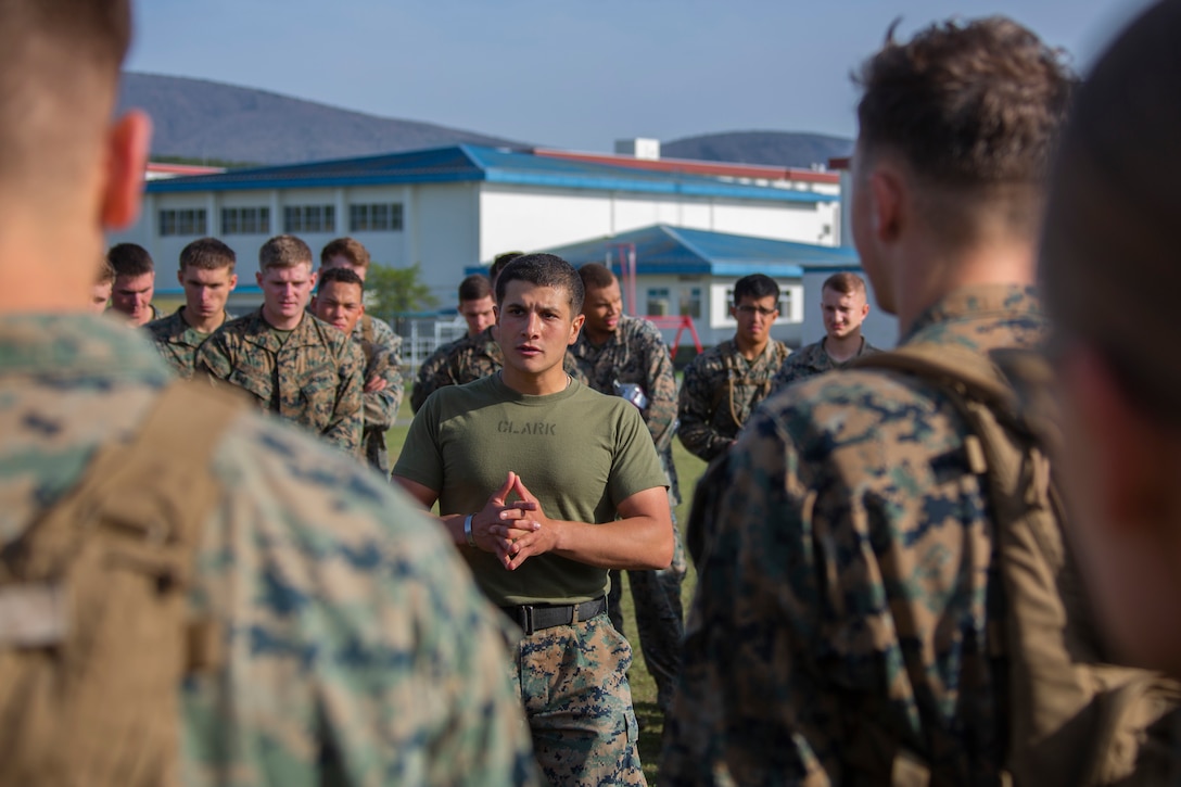 A Marine stands in the middle of a circle of Marines.