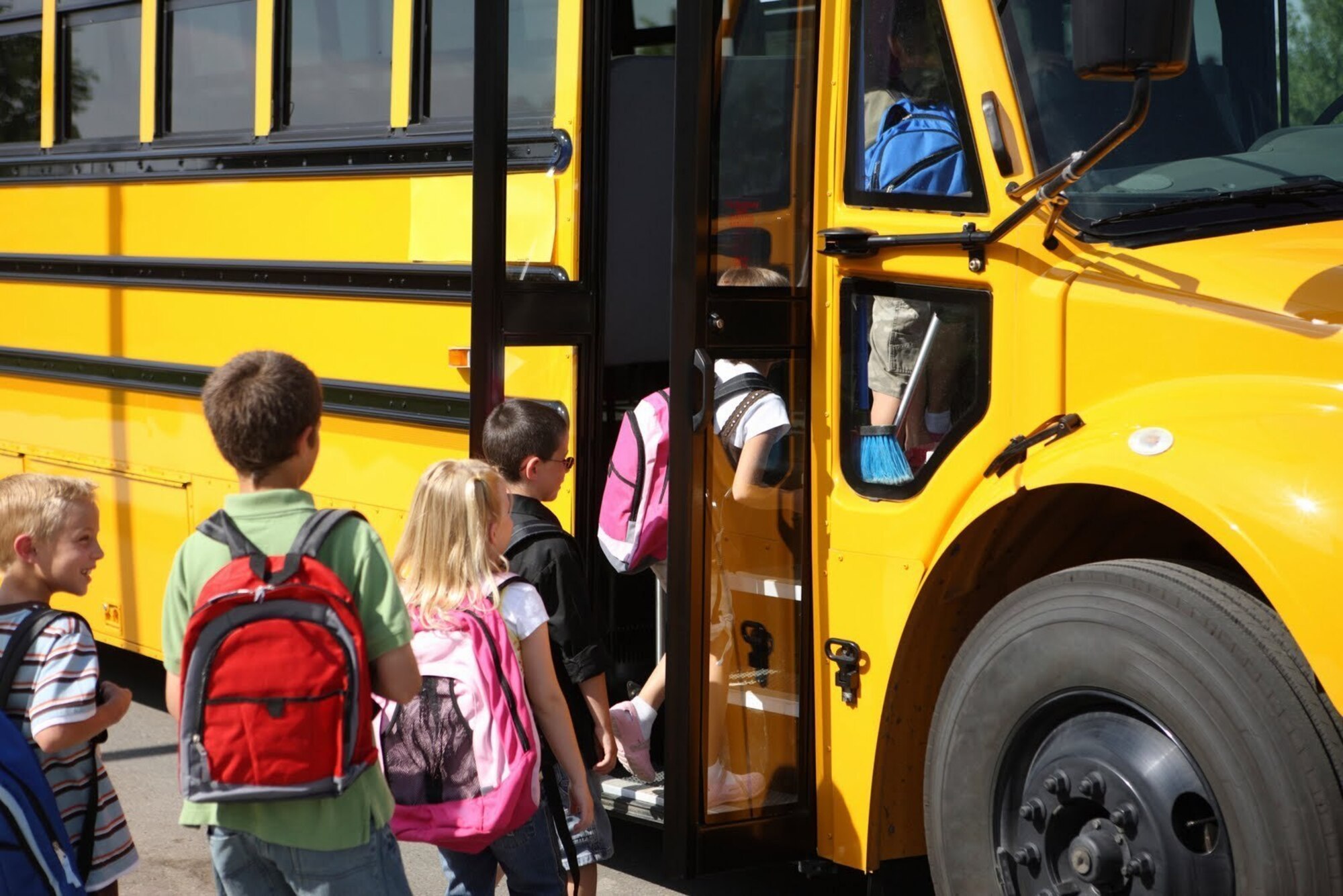 School children loading onto a school bus.