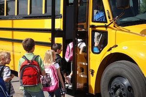 School children loading onto a school bus.