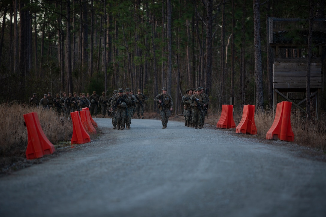 A group of Marines hike down a road.