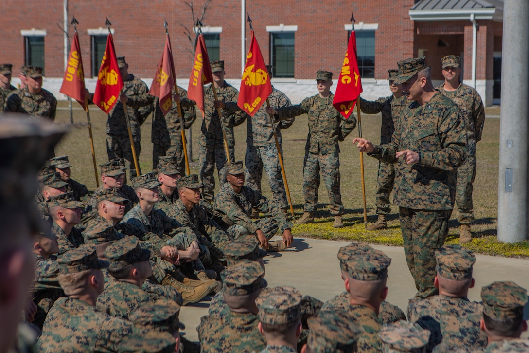 A Marine speaks to a group of Marines seated.