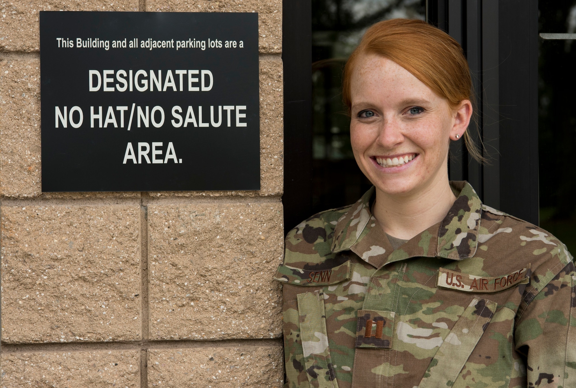 U.S. Air Force Capt. Emilee Senn, 337th Recruiting Squadron operations flight commander, stands next to a designated No Hat/No Salute area sign at the 20th Force Support Squadron Child Development Center at Shaw Air Force Base, South Carolina, Aug. 27, 2019.