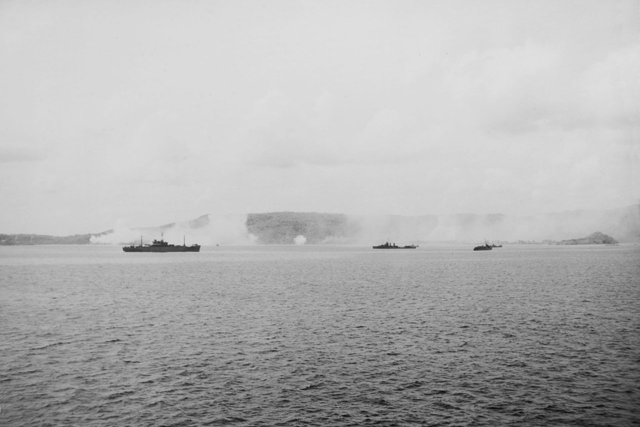 Navy ship guns fire on island.