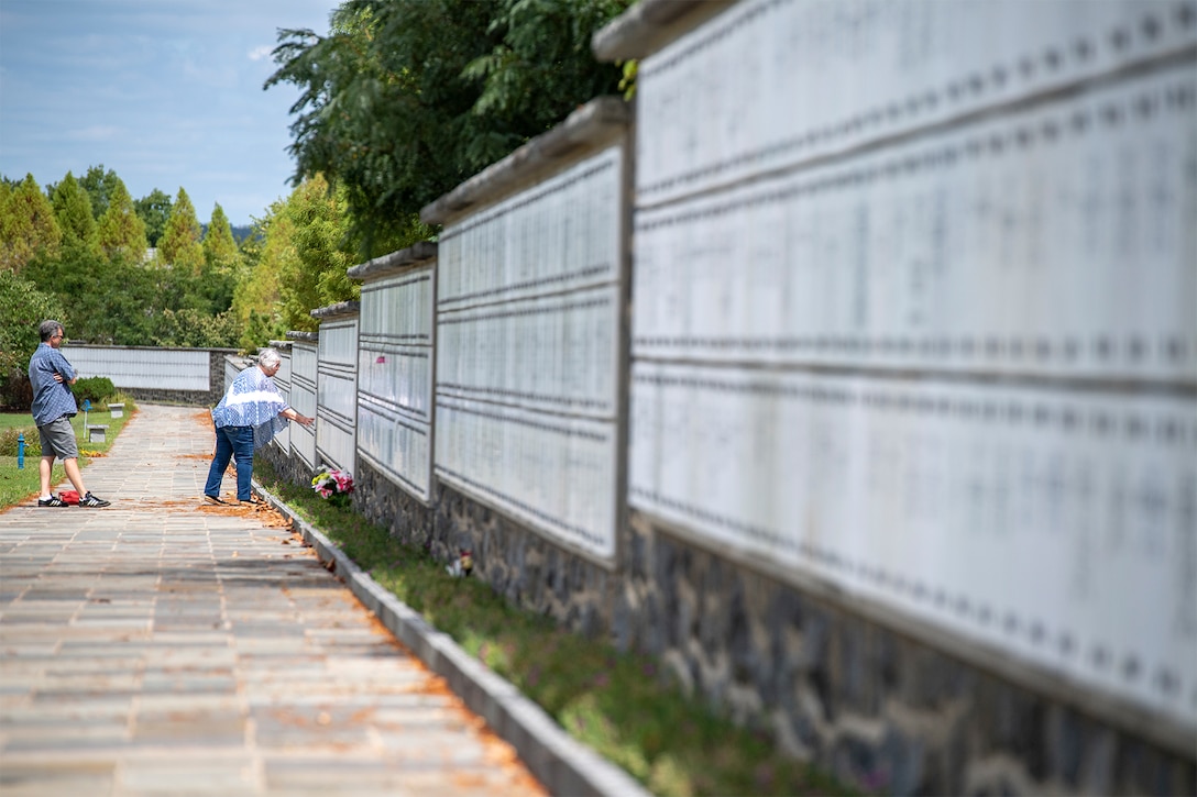 Visitors observe a wall at Arlington National Cemetery.