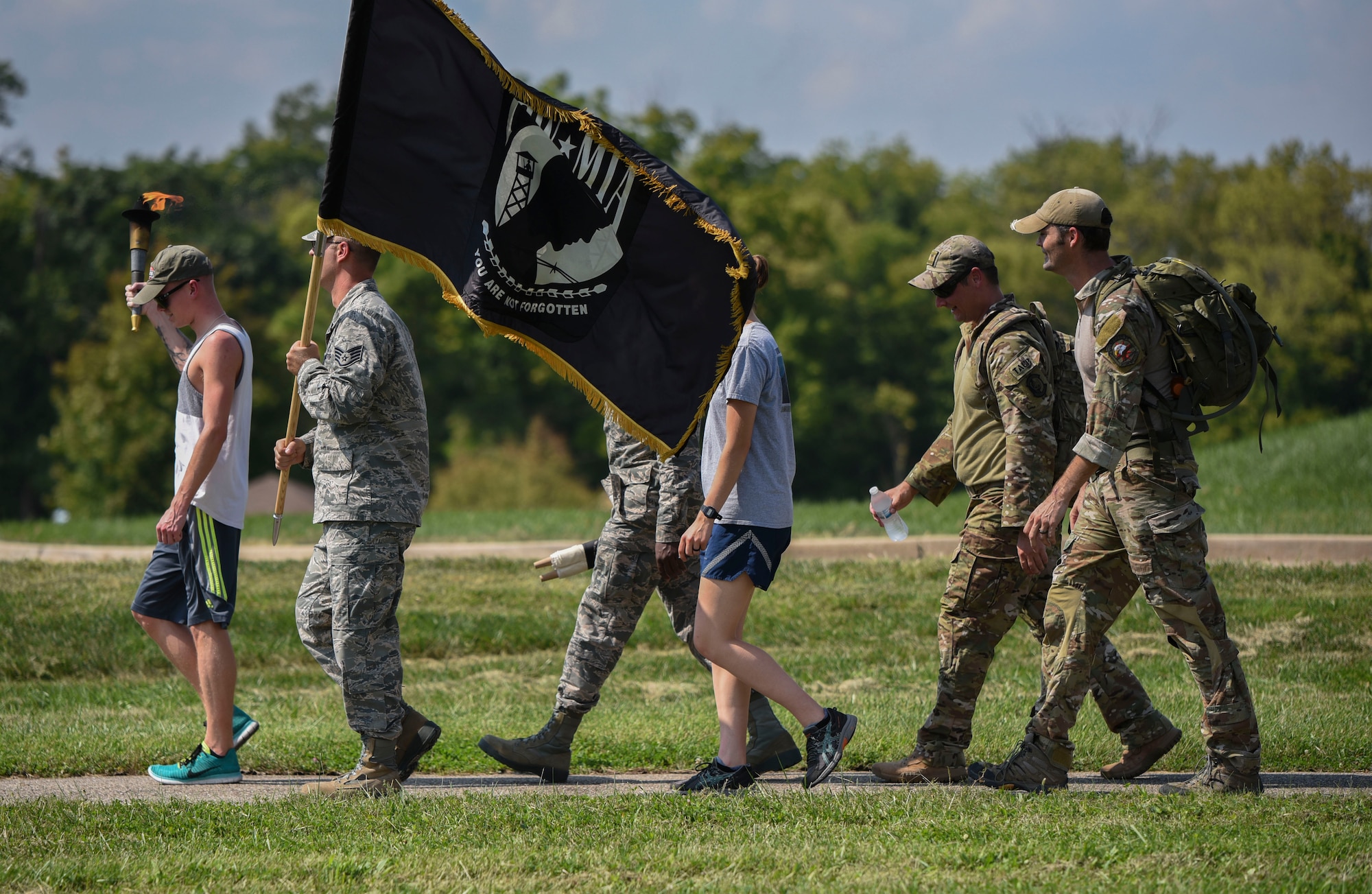Volunteers from the National Air and Space Intelligence Center, carry the POW/MIA flag, scroll, and torch during the annual POW/MIA walk/run on Wright-Patterson Air Force Base, Ohio, Sept. 20, 2018. Runners/walkers carried the POW/MIA flag and torch continuously for 24 hours to honor all past and present POW/MIA. (U.S. Air Force photo by Senior Airman Holly Ardern)