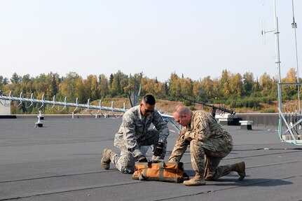 Master Sgt. Jamie Heinzelman and Staff Sgt. Preston Fernandez works on adjusting a radio antenna at Joint Base Elmendorf Richardson, Alaska, Aug. 28, 2019.