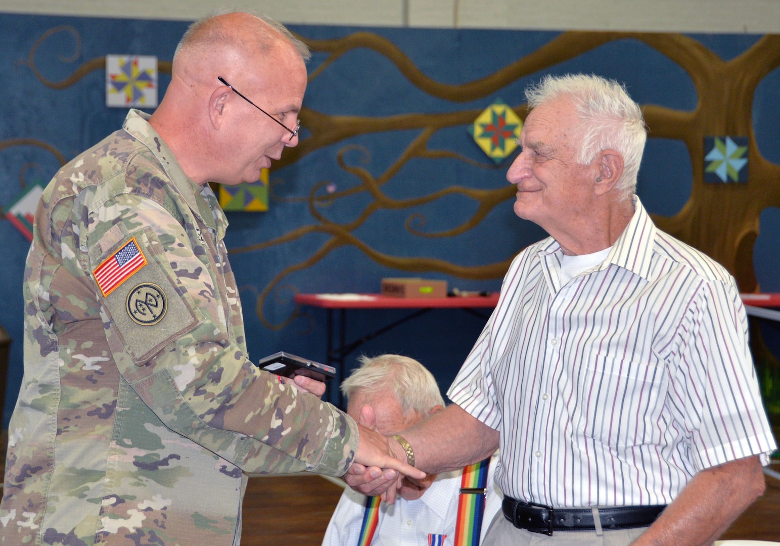 Maj. Gen. Ray Shields, the adjutant general of New York, presents a military challenge coin to Air Force Korean War veteran Merton W. Houghton during an awards ceremony at the former New York State Armory in Hoosick Falls, N.Y., on Aug. 28, 2019. Shields honored 10  local veterans with New York state awards recognizing their military service during the event.