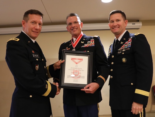 ​E. Scott Lowdermilk (center), the Transatlantic Division Chief of Plans and Operations, receives the Army Engineer Association's Silver Order of the de Fleury Medal at his retirement ceremony from both the military and civilian service on Aug. 2, 2019, after a career that spanned 38 years. Presenting the award to Lowdermilk are Maj. Gen. Donald Jackson (left) and Maj. Gen. Robert Carlson (right).