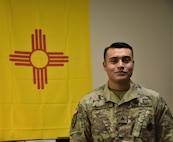 Sgt. Ignacio Alvarez, recruiter, Gallup Recruiting Station, Albuquerque Recruiting Company, Phoenix Recruiting Battalion, poses in front of the New Mexico state flag in his recruiting station, Gallup, N.M., Aug. 22. Alvarez, a Gallup native, returned to his hometown as a recruiter in Nov. 2017, having left 6 years earlier to join the Army.
