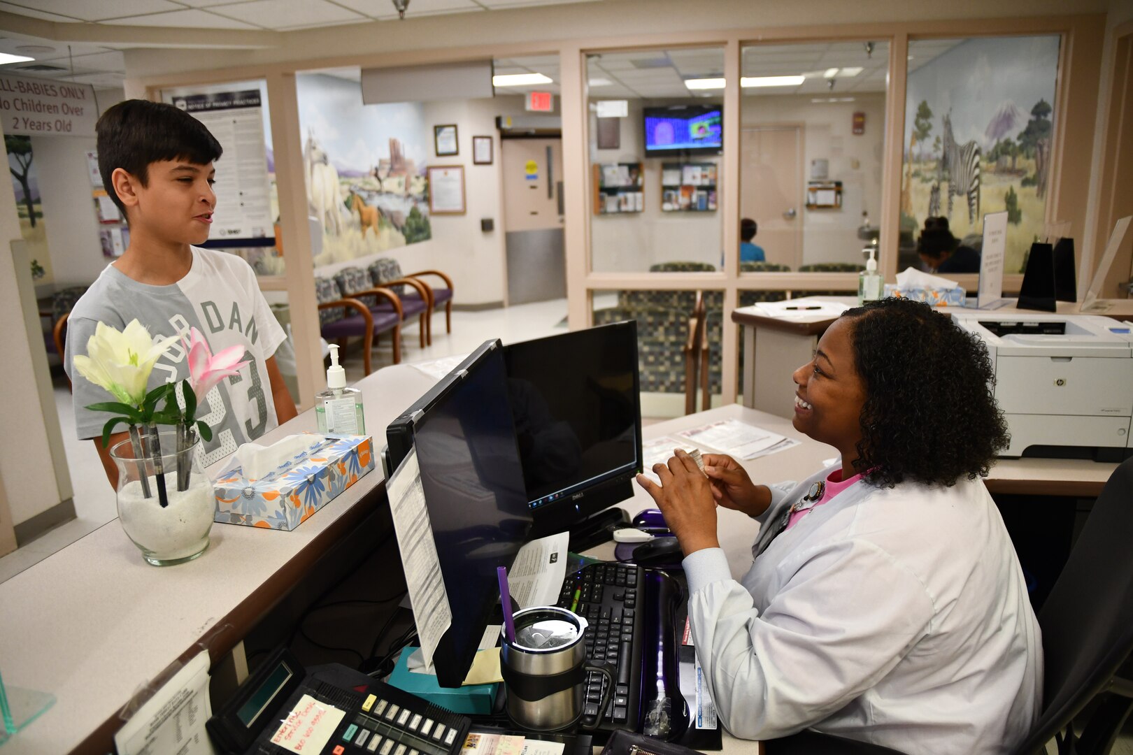 Yamoca Joseph, a medical support assistant in Kenner Army Health Clinic's Wilkerson Pediatric Clinic, checks the credentials of 14-year-old Jayden Rios prior to an appointment.