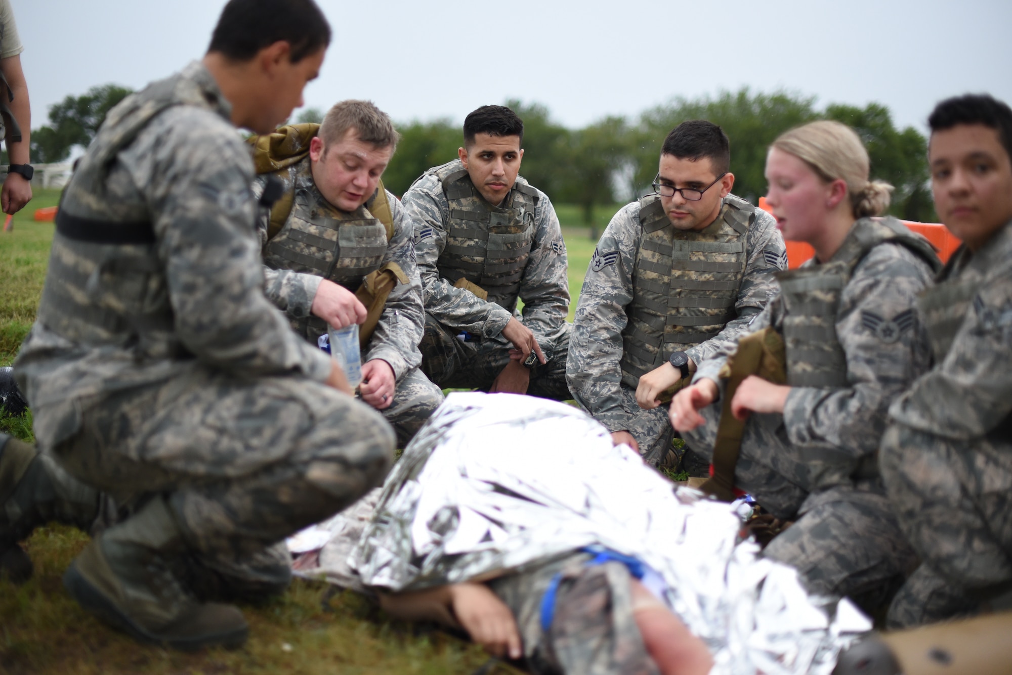 Members of the 22nd Medical Group discuss the strategy needed to perform Tactical Combat Casualty Care on an Airman with simulated wounds during an Emergency Medical Technician Rodeo Aug. 22, 2019, at McConnell Air Force Base, Kan. The TCCC course replacing the Self Aid and Buddy Care Program are tentatively scheduled to begin at the end of 2019 for Airmen across McConnell. (U.S. Air Force photo by Airman 1st Class Alexi Myrick)