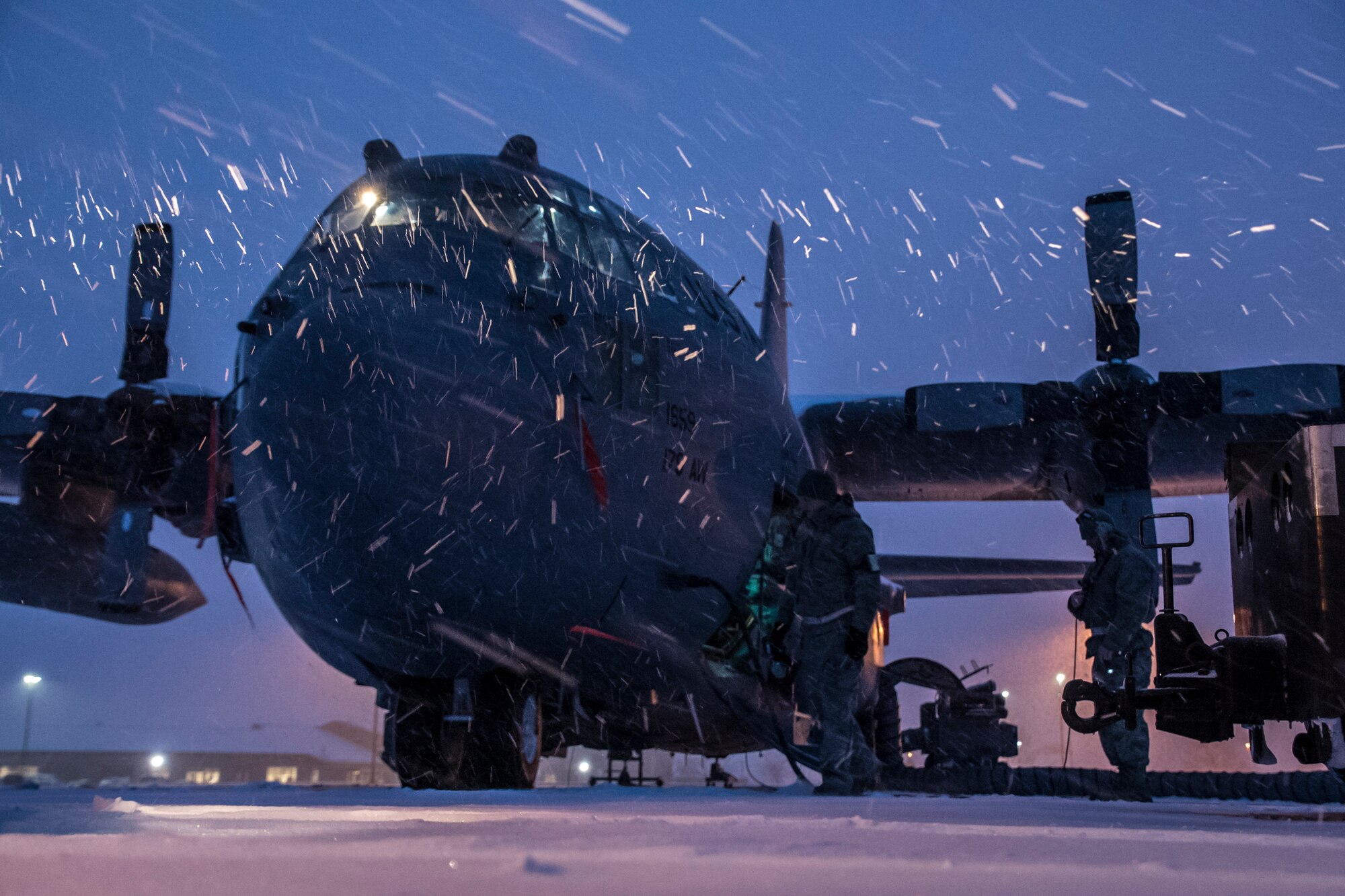 A photo of a C-130 in the early morning during a snowstorm.